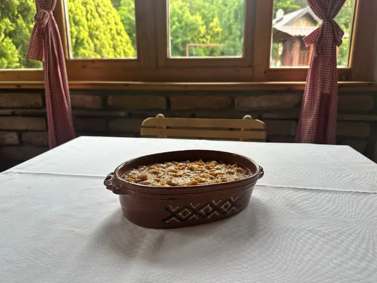 Pasulj prebranac u glinenoj posudi na stolu kraj prozora
