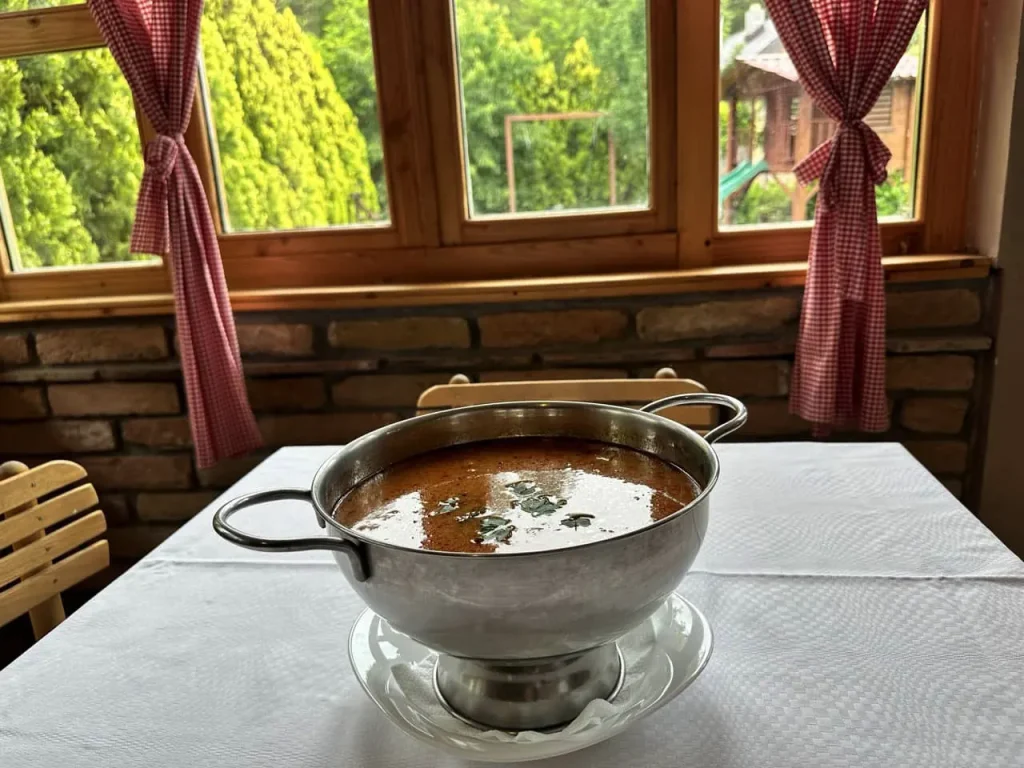 Riblja čorba u posudi na stolu postavljenom za ručak, kraj prozora