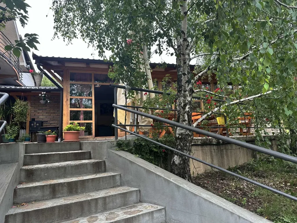 Ulaz u Restoran Groš: betonske stepenice sa rukohvatom vode do drvenih ulaznih vrata